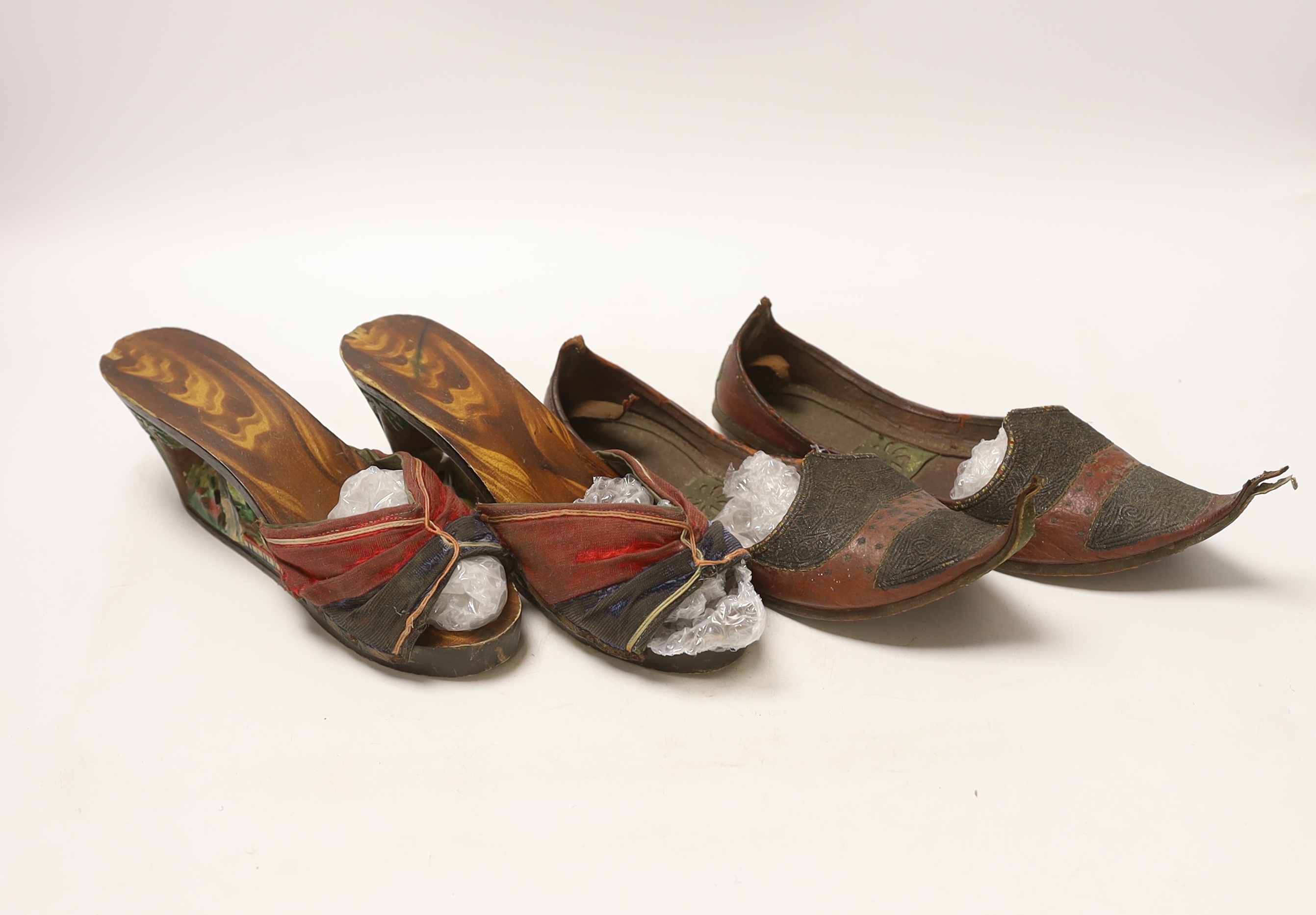 Two pairs of shoes; a small pair of novelty carved wooden heeled clogs with Philippine’s 1945 painted on the back of the heels and a carved house and mountainous scene within the heel and sole, together with a pair of le